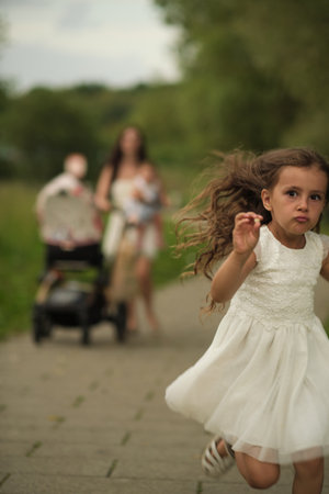 Child sprints joyfully on a path, family in the background; symbolizing youthful energy and active lifestyles.の写真素材