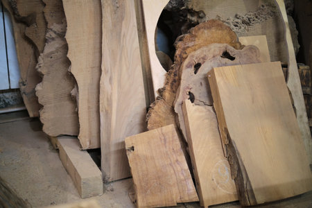 Rough-cut wood slabs lean in a workshop, natural patterns highlighted. Eco-conscious woodcraft resonates with sustainability trends.の写真素材