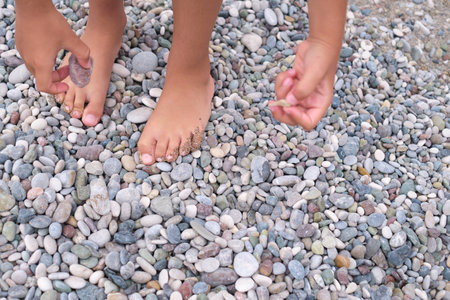 Childs feet and hands engage with a myriad of stones, illustrating active discovery.の写真素材