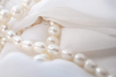The tender arrangement of pearls on a gentle white cloth exudes a serene aesthetic. Its a quiet protest against the glaring, artificial visuals that dominate modern digital platforms.の写真素材
