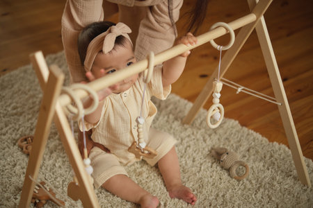 With focused eyes, a baby interacts with eco-friendly toys, grasping at natures shapes. Reflects a growing awareness and motor skills.の写真素材