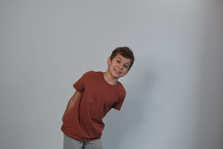 boy tilts with a playful grin, casual in a tee and sweatpants. The pose reflects the authenticity trend in imagery, eschewing staged perfection. move towards genuine, relatable content in media.の写真素材