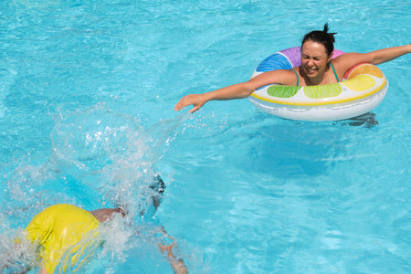 A child advances in water towards a waiting float, mothers arms open; safety and learning in the...