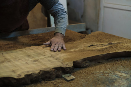 Hands carefully handle a uniquely shaped wooden slab, showcasing its organic curves. Its woodworking with respect for nature.の写真素材