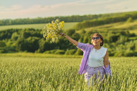 mature Asian woman lifts a bouquet, her face a canvas of peace; celebrating life s latter stages with natural grace.の写真素材