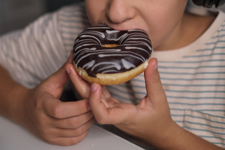 A child enjoys a delicious donut while wearing headphones, illustrating the pleasures of a sweet treat paired with good music. Captures a modern, indulgent moment.の写真素材