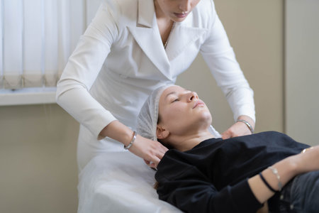 A cosmetologist gently adjusts her clients head during a skincare treatment. This image highlights...