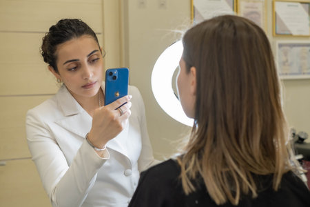 A cosmetologist documents a successful treatment outcome, using technology to enhance business presence and client trust.の写真素材