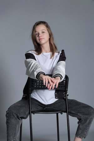 A young girl in a jacket smiles softly as she leans forward. The natural lighting and close-up shot emphasize her youthful energy and laid-back attitude.の写真素材