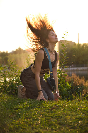 A woman, bathed in warm evening light, kneels by a peaceful lake, her expression open and sincere....
