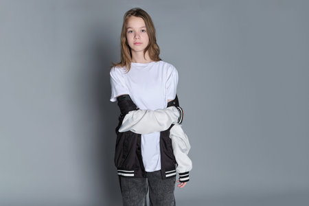 A teenage girl in a relaxed, modern outfit holds her jacket, conveying a sense of style and freedom. This image reflects the trend of embracing casual fashion as a form of personal expression.の写真素材