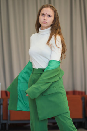 A young woman in a striking green suit gazing thoughtfully into the distance. Her expressive face suggests contemplation or focus.の写真素材