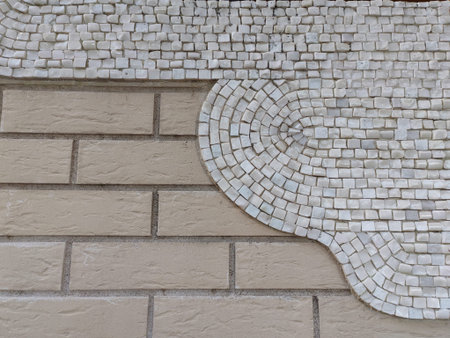 A minimalistic mosaic design featuring white tiles in a semi-circular pattern against a beige brick...