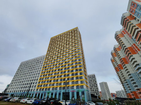A pastel-colored high-rise residential building with curved balconies and windows, set above a courtyard. The architecture showcases modern urban development and the growing demand for multi-story city living.の写真素材
