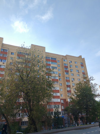 A modern apartment building with a red and beige brick facade, multiple windows, and balconies. This urban structure highlights the straightforward design and functionality of residential housing in busy cities.の写真素材