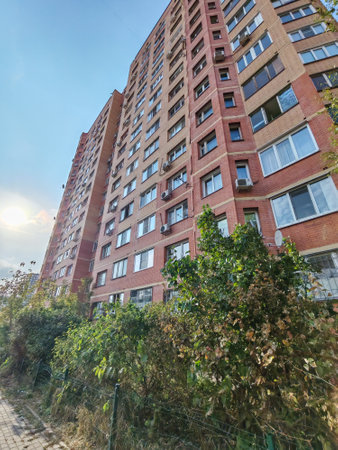 A modern apartment building with a red and beige brick facade, multiple windows, and balconies. This urban structure highlights the straightforward design and functionality of residential housing in busy cities.の写真素材