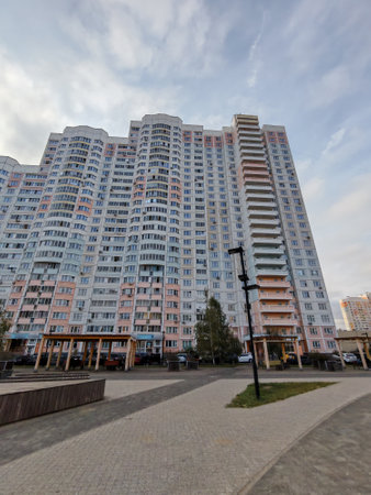 A large multi-story residential building with a pastel color palette of pink, white, and blue, featuring numerous balconies. The high-rise structure represents modern city living with an expansive courtyard below.の写真素材
