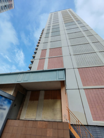 A tall apartment building with pastel-colored balconies and windows, located in a residential area. The structure captures the urban residential lifestyle, emphasizing functionality and density in modern city planning.の写真素材