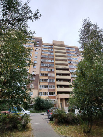 A pastel-colored high-rise residential building with curved balconies and windows, set above a courtyard. The architecture showcases modern urban development and the growing demand for multi-story city living.の写真素材