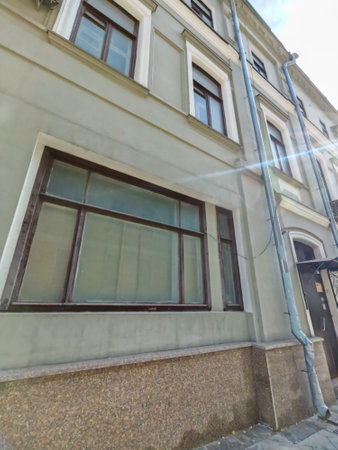 A worn facade of a historic building with rectangular windows and aged plaster. The image captures the character of urban decay and the need for restoration in historic districts.の写真素材