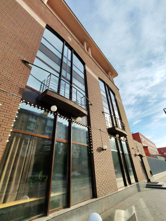 A modern building with large floor-to-ceiling windows framed by brick walls, reflecting the surrounding cityscape. The photo highlights contemporary window installation and architectural designの写真素材