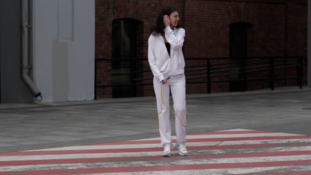 A woman in athletic clothing stands on a red-and-white crosswalk, preparing for a workout. The contrast between city elements and sports gear highlights the balance between fitness and modern urban life.の写真素材