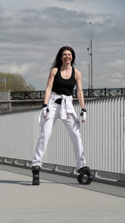 A determined woman performs energetic jumps with special shoes, set against a backdrop of historic bridges. This fusion of old and new symbolizes the continuous evolution of fitness in the modern worの写真素材