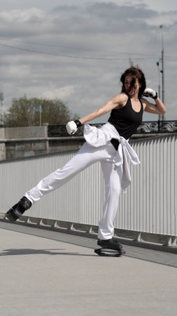 A woman in jumping boots performs a high kick, showcasing strength and agility. This dynamic moment highlights power, control, and advanced balance skills.の写真素材
