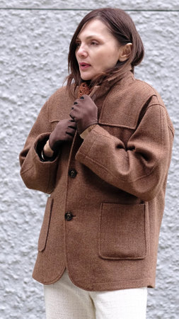 An elderly woman braving the cold, thoughtfully wrapping herself in her coat. The photo symbolizes the physical and emotional shifts of menopause and a new life chapter.の写真素材