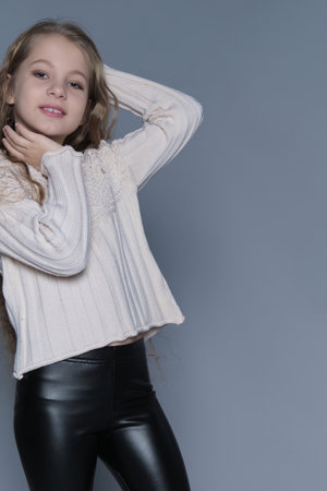 A young girl poses playfully, resting one hand on her face and the other behind her head. Her confident and relaxed expression embodies self-expression and natural beauty, making this image ideal for themes of youth and individuality.の写真素材
