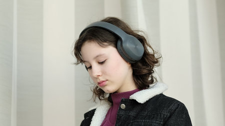 A girl with headphones looks upward with a composed and introspective gaze. The photo conveys themes of contemplation, individuality, and immersive sound experiences.の写真素材