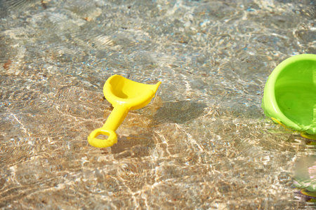 Colorful beach toys drift alone in clear water near the shore.の写真素材