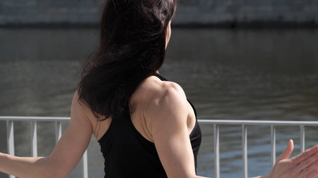 A strong woman raises her arms, showcasing toned muscles and determination. This image represents fitness, self-discipline, and body confidence.の写真素材