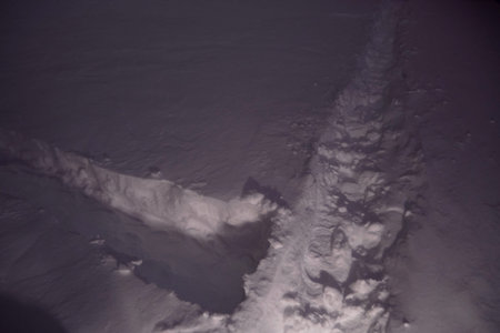 Fresh footprints in deep snow on a quiet winter night illuminated by dim city lights. The cold...