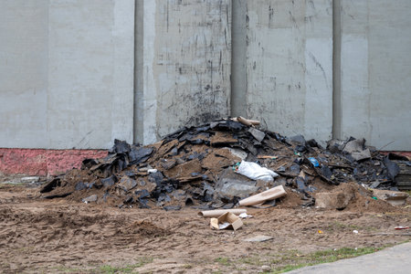 Roofing felt pile, sand and other construction waste against the wall of a building, building reconstruction, waste sorting, hazardous waste disposal at a construction site, waste recyclingの写真素材