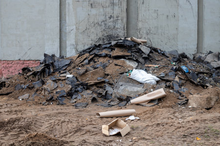 Old roofing felt waste against a building wall after renovation. Concepts for waste sorting, hazardous waste disposal at construction sites, and waste recycling.の写真素材