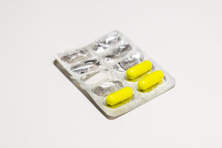 Semi-empty blister pack isolated on white background. Metal blister for capsules. Healthcare and...