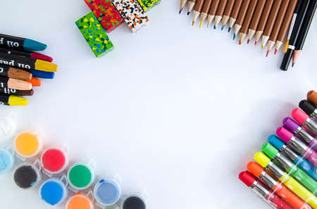 Paints, pencils, crayons, colored pens on a white background, in the center of the free space. School supplies are laid out on the table in a circle. Drawing circle for children. Big album sheet.の写真素材