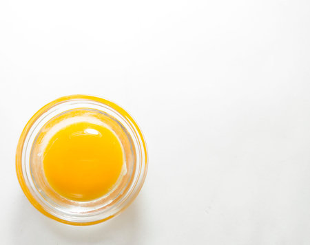 An egg in a small bowl. Round egg on a light background. Raw egg removed from the top.