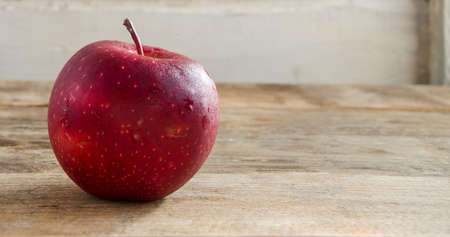 A good snack. A red, ripe apple on a wooden background. Copy space. A natural and healthy fruit. Harvesting apples. Natural vitamins in fruits.の写真素材