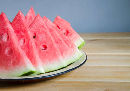 Sliced, ripe watermelon on a tray. Sweet berries on a wooden table. Summer fruit is cut into slices. Natural juice and vitamins in one watermelon.の写真素材