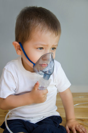 Boy, European appearance cold and doing inhalation. A 3-year-old baby is being treated with a nebulizer. The child is not feeling well.の写真素材