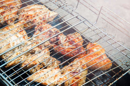 Barbecue chicken on live fire. Marinated meat is fried on the grill. Picnic in nature with family. Barbecue on a grid with a delicious, crispy crust.の写真素材