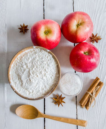 Fresh, red apples and other ingredients, on a wooden background, for apple pie. Food and eco, wooden utensils on a white table. Flat lay.の写真素材