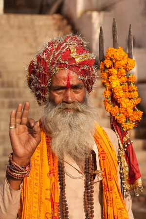 VARANASI,INDIA - March 20,2013 : Unidentified sadhu salutes people and sits on the streets of Varanasi,Indiaのeditorial素材