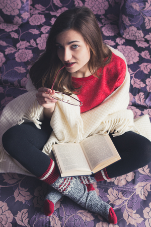 girl reading a book in a warm blanketの写真素材