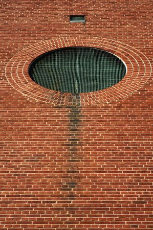 Circular grate with verdigris set in brick wall.の写真素材
