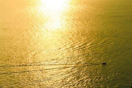 Golden sea with moving boat under sunsetの写真素材