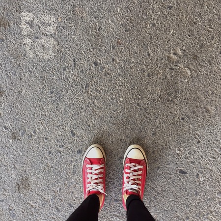 Red Sneakers Shoes Walking On Dirty Concrete Top View , Canvas Shoes Walking On Concrete Great For Any Use.の写真素材