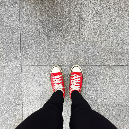 Closeup of Legs Wearing Black Jeans and Red Sneakers on Floor or Ground Background great for any use.の写真素材